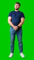Man standing with a thoughtful expression in a casual outfit against a green background photo