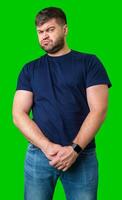 Man standing with a thoughtful expression in a casual outfit against a green background photo