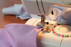 Sewing machine in use on a wooden table, stitching a light fabric in a well-lit indoor workspace photo