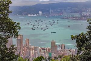 Aerial view of cargo ships anchored near Hong Kong port, with urban skyline and mountains in the background photo