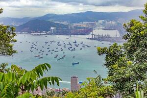 Aerial view of cargo ships anchored near Hong Kong port, with urban skyline and mountains in the background photo