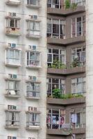 Close-up of a residential building facade with detailed windows, plants, and signs of everyday urban life photo