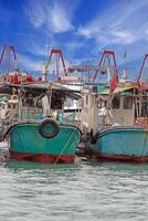 Traditional fishing boats docked in a harbor under a bright blue sky, showcasing rustic maritime charm photo