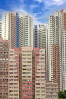 Dense urban architecture in Hong Kong with tightly packed high-rise buildings under a bright sky photo