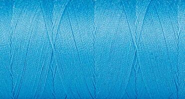 Texture of threads in a spool of blue color on a white background photo