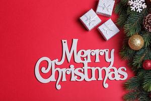 beautiful branches of a Christmas tree with cones and toys on a red background with the inscription Merry Christmas photo