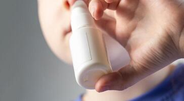 A caucasian girl puts drops into her nose and an anti-inflammatory spray for nasal congestion. Treatment of runny nose and sinusitis. Antibiotic medicinal spray, close-up photo