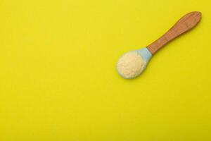 Dairy-free wheat porridge with pumpkin in a spoon on a yellow background. The concept of feeding a baby vitamin-mineral cereals for health and strengthening the immune system. Copy space for text photo