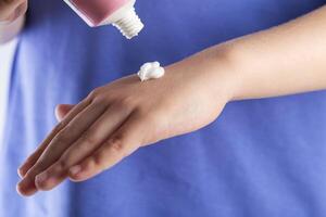 The hands of a girl apply a medicinal cream against chapping of the skin on a white background. Moisturizing and protective hand cream, close-up photo