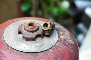 A broken gas cylinder valve lies on a red cylinder. Danger of gas leakage and explosion. Copy space for text, butane. Safety precautions photo