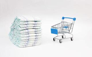 Baby diapers on a white background and a shopping trolley, the concept of buying hygiene products for the child, close-up, demand photo