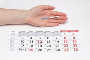 A girl holds a hand with a negative rate of pregnancy test on the background of the calendar, the day of ovulation, infertility photo