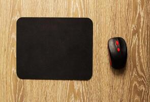 Computer mat and computer mouse on a wooden background, close-up, black computer mat photo