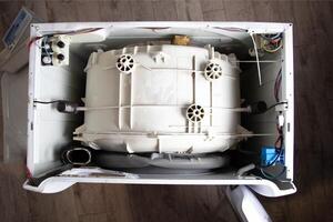 Top view of a disassembled washing machine. Replacing the washing machine drum and water supply valves. Call a washing machine repair technician to your home, industry photo