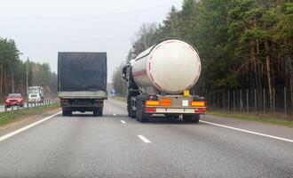 A truck with a semi-trailer tanker transports dangerous cargo along the highway - liquefied gas. Logistics of dangerous goods. Copy space for text photo