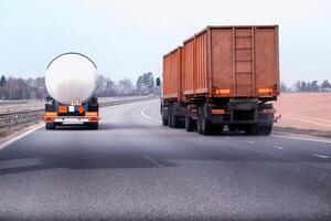 A truck with a semi-trailer tanker transports dangerous cargo along the highway - liquefied gas. Logistics of dangerous goods. Copy space for text photo