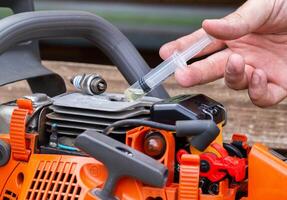 Injection of fuel from a syringe into the combustion chamber of a chainsaw. Checking the carburetor system and chainsaw ignition system. Close-up photo