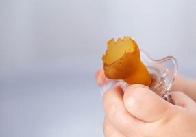 A baby's pacifier is chewed and torn in a baby's hand, close-up. Concept of teething in children, problems with bite. Copy space for text photo