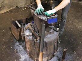 The blacksmith in the forge makes a metal part on the anvil, close-up. Industry photo