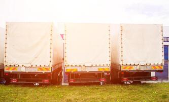 Freight vans stand in a row, rear view, trucking industry and sun, trucking photo