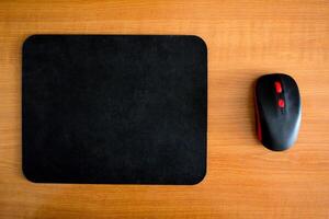 Computer mat and computer mouse on a wooden background, close-up, modern photo
