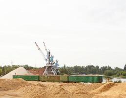 The port crane makes loading of wood chips into the freight cars of the train, loading photo