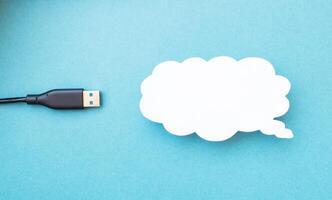 Cloud for data storage cut from paper on a blue background and cable usb, close-up, data storage on the Internet photo