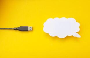 Cloud for data storage cut from paper on a yellow background and cable usb, close-up, data storage on the Internet photo