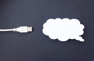 Cloud for data storage cut from paper on a black background and cable usb, close-up, data storage on the Internet photo