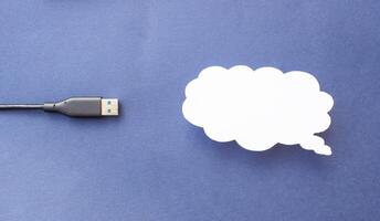 Cloud for data storage cut from paper on a blue background and cable usb, close-up, data storage on the Internet photo