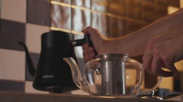 Close-up of a man pouring boiling water into a teapot with tea leaves video