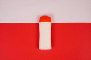 Plastic shampoo bottle with flip-top lid isolated on red and white background. MockUp template for your design. Empty and clean packaging for cosmetic product. File contains clipping path. photo