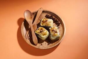 Banana Bolen is made from bananas and pastry dough, filled with chocolate and cheese. It is served on a wooden plate in a selective focus style image. photo