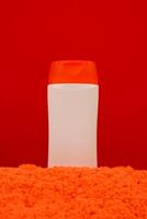 Plastic shampoo bottle with flip-top lid isolated on orange sand background. MockUp template for your design. Empty and clean packaging for cosmetic product. File contains clipping path. photo