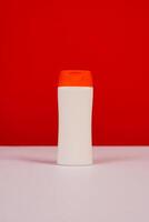 Plastic shampoo bottle with flip-top lid isolated on red and white background. MockUp template for your design. Empty and clean packaging for cosmetic product. File contains clipping path. photo