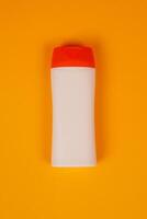 Plastic shampoo bottle with flip-top lid isolated on orange background. MockUp template for your design. Empty and clean packaging for cosmetic product. File contains clipping path. photo