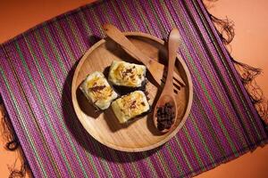 Banana Bolen is made from bananas and pastry dough, filled with chocolate and cheese. It is served on a wooden plate in a selective focus style image. photo