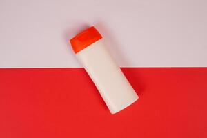 Plastic shampoo bottle with flip-top lid isolated on red and white background. MockUp template for your design. Empty and clean packaging for cosmetic product. File contains clipping path. photo