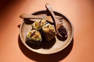 Banana Bolen is made from bananas and pastry dough, filled with chocolate and cheese. It is served on a wooden plate in a selective focus style image. photo