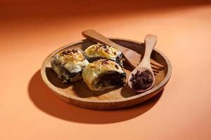 Banana Bolen is made from bananas and pastry dough, filled with chocolate and cheese. It is served on a wooden plate in a selective focus style image. photo