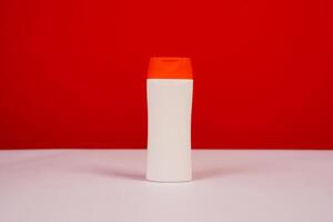 Plastic shampoo bottle with flip-top lid isolated on red and white background. MockUp template for your design. Empty and clean packaging for cosmetic product. File contains clipping path. photo
