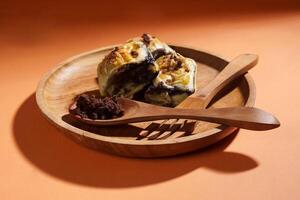Banana Bolen is made from bananas and pastry dough, filled with chocolate and cheese. It is served on a wooden plate in a selective focus style image. photo