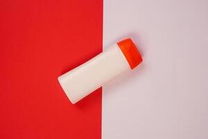 Plastic shampoo bottle with flip-top lid isolated on red and white background. MockUp template for your design. Empty and clean packaging for cosmetic product. File contains clipping path. photo