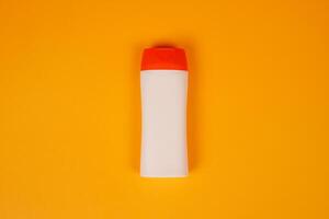 Plastic shampoo bottle with flip-top lid isolated on orange background. MockUp template for your design. Empty and clean packaging for cosmetic product. File contains clipping path. photo
