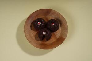 steamed brownie cake with a layer of red and white cream in the middle, served on a wooden plate isolated on yellow background photo