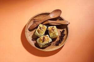 Banana Bolen is made from bananas and pastry dough, filled with chocolate and cheese. It is served on a wooden plate in a selective focus style image. photo