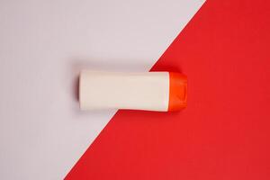 Plastic shampoo bottle with flip-top lid isolated on red and white background. MockUp template for your design. Empty and clean packaging for cosmetic product. File contains clipping path. photo