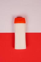 Plastic shampoo bottle with flip-top lid isolated on red and white background. MockUp template for your design. Empty and clean packaging for cosmetic product. File contains clipping path. photo