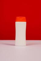Plastic shampoo bottle with flip-top lid isolated on red and white background. MockUp template for your design. Empty and clean packaging for cosmetic product. File contains clipping path. photo