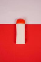 Plastic shampoo bottle with flip-top lid isolated on red and white background. MockUp template for your design. Empty and clean packaging for cosmetic product. File contains clipping path. photo